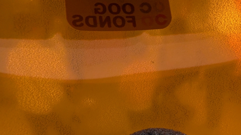 Ongedraaide close-up van een amberkleurige fles of container met een deels zichtbare tekst op het oppervlak.