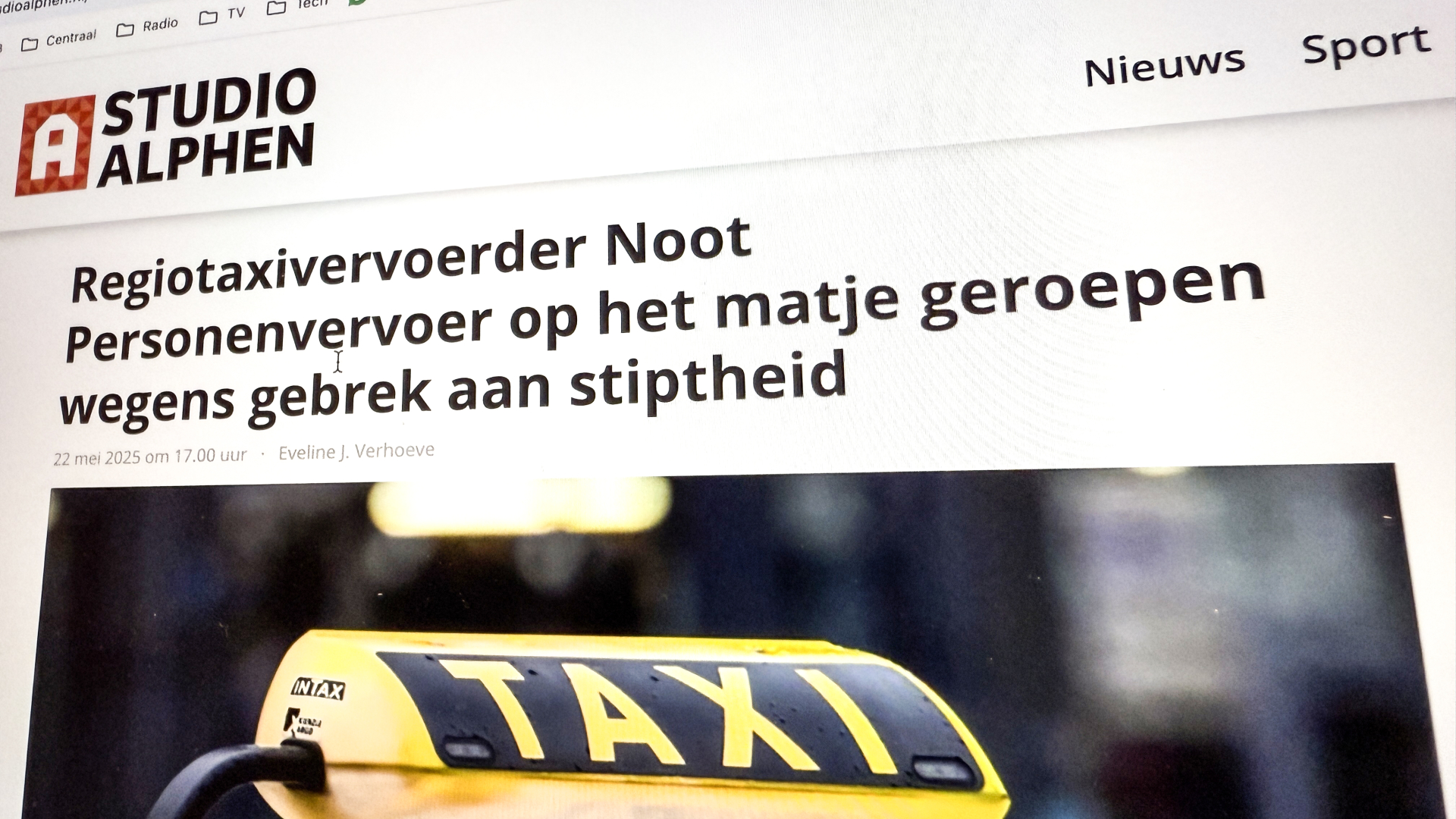 Een nieuwsartikel op de website van Studio Alphen met de titel 'Regiotaxivervoerder Noot Personenvervoer op het matje geroepen wegens gebrek aan stiptheid' en de afbeelding van een taxibord.