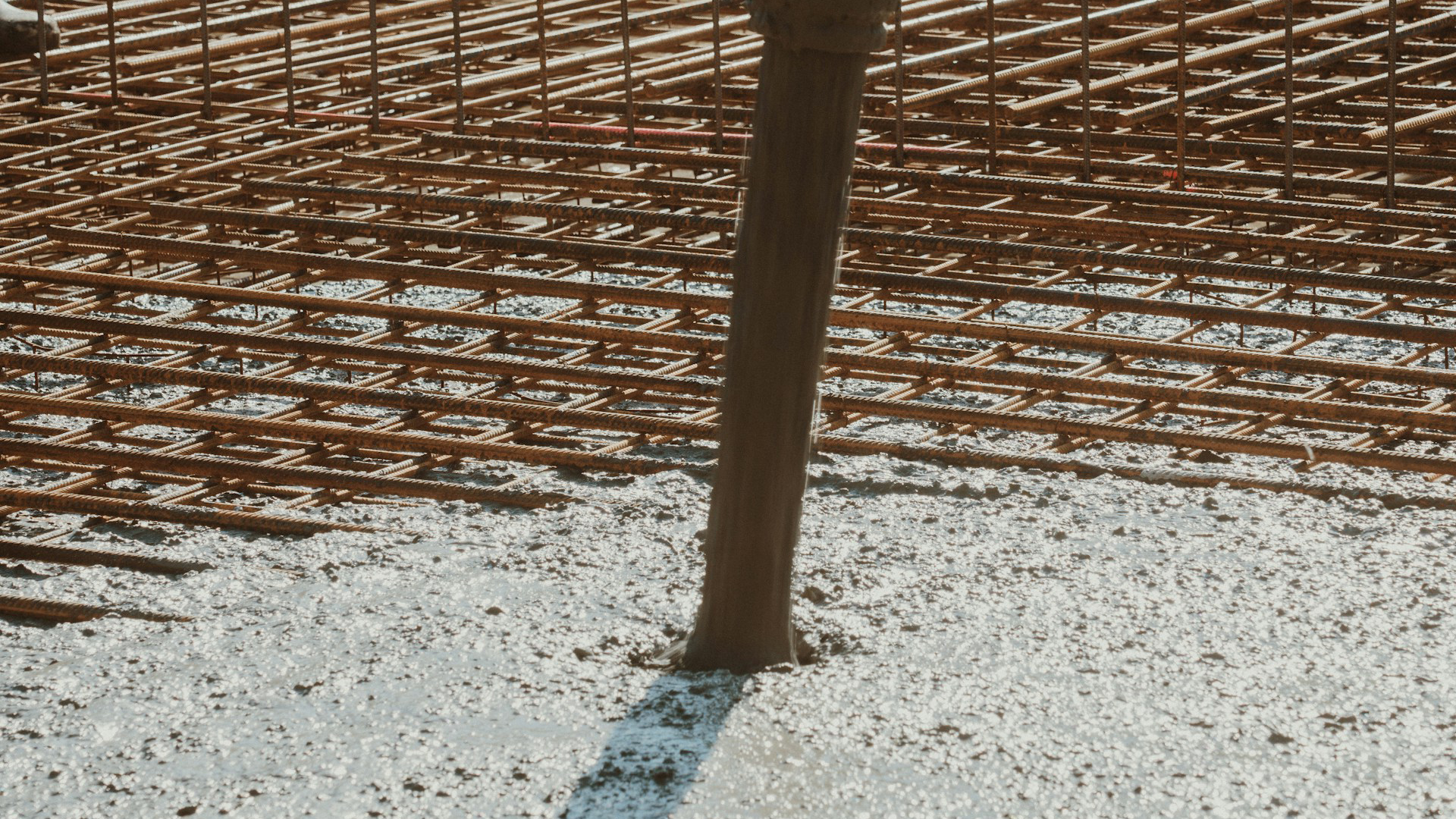 Een betonnen vloer wordt gestort op een stalen wapeningsnet.