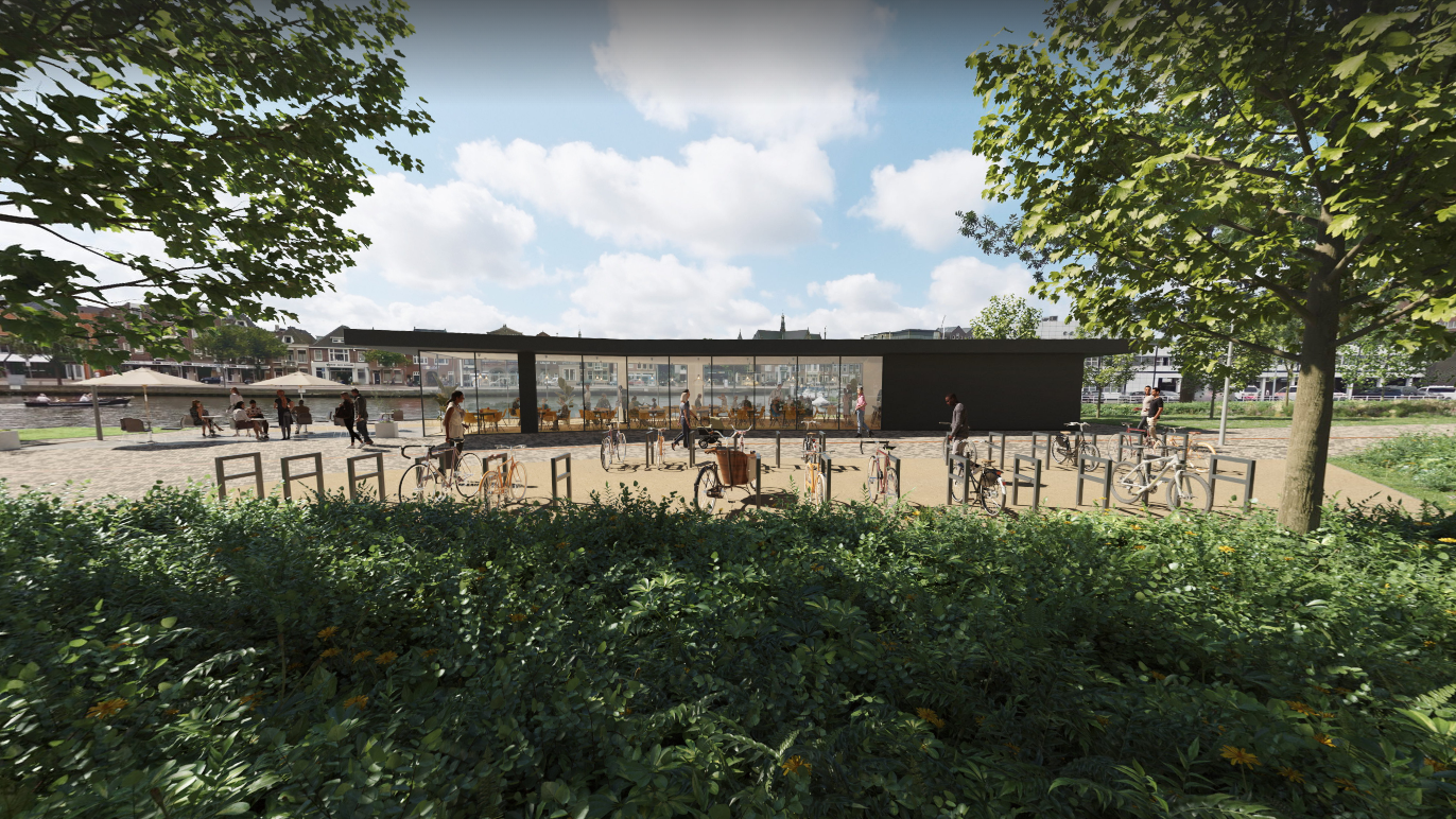 Een moderne fietsenstalling met verschillende fietsen geparkeerd, omringd door groen en bomen, met op de achtergrond een gebouw met grote glazen ramen en een terras met tafels en parasols waar mensen zitten.