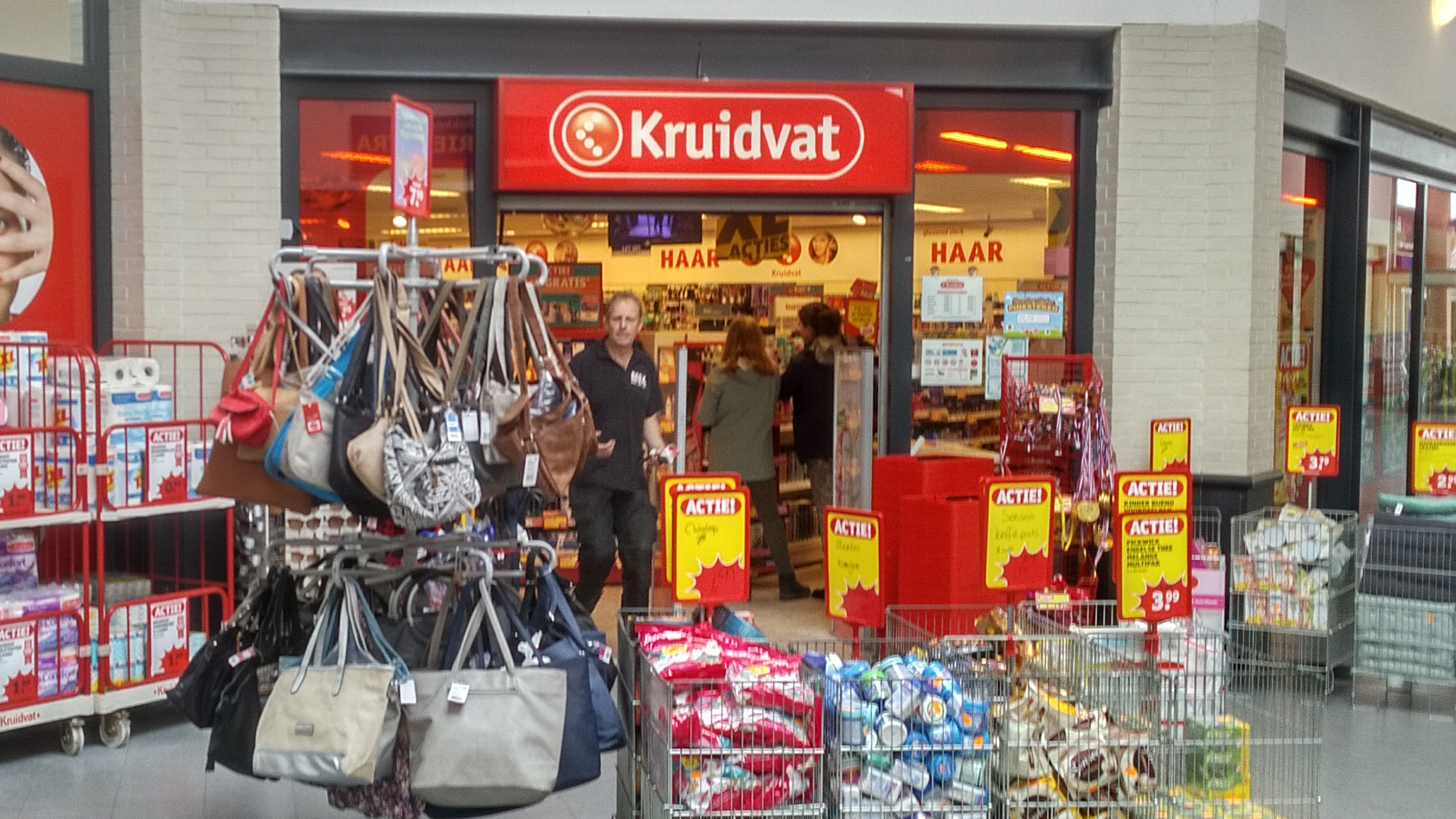 Ingang van een Kruidvat-winkel met uitgestalde tassen, aanbiedingen en winkelwagentjes.