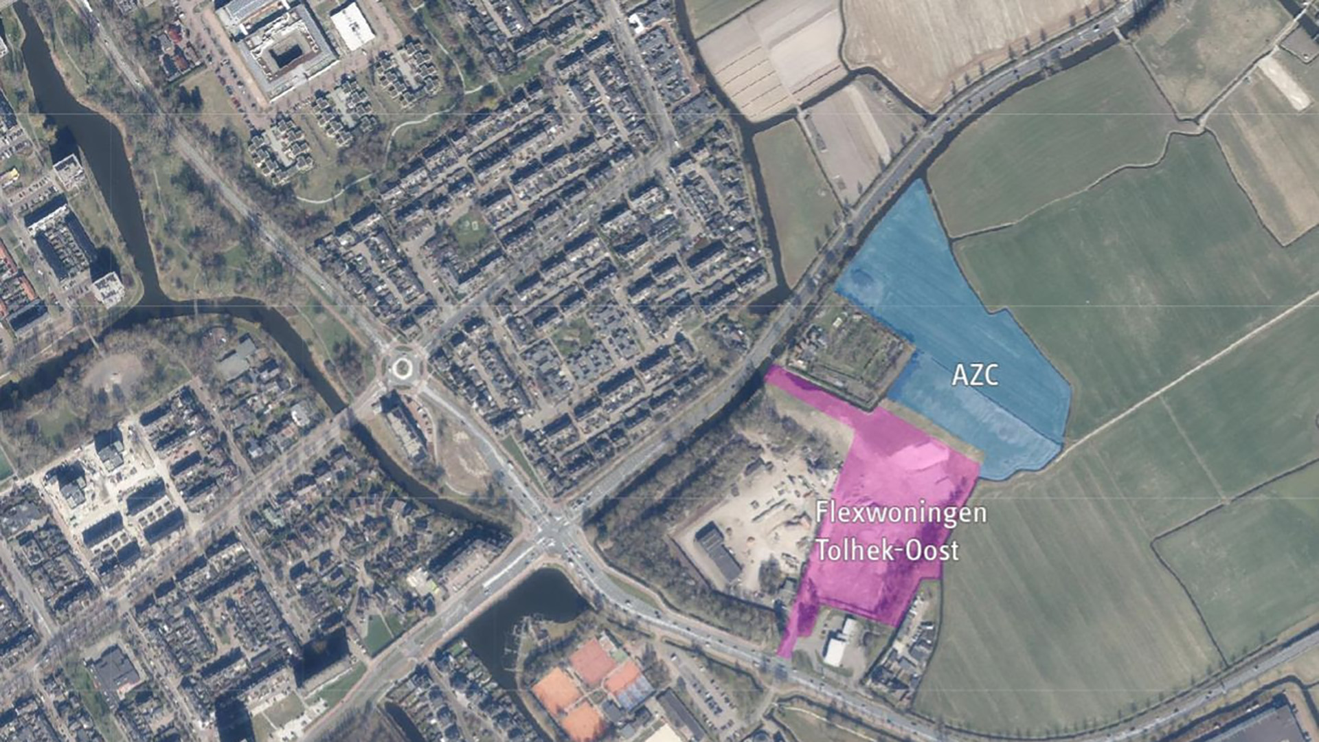 Satellietbeeld van een woonwijk naast weilanden, met gemarkeerde gebieden "AZC" in blauw en "Flexwoningen Tolhek-Oost" in roze.
