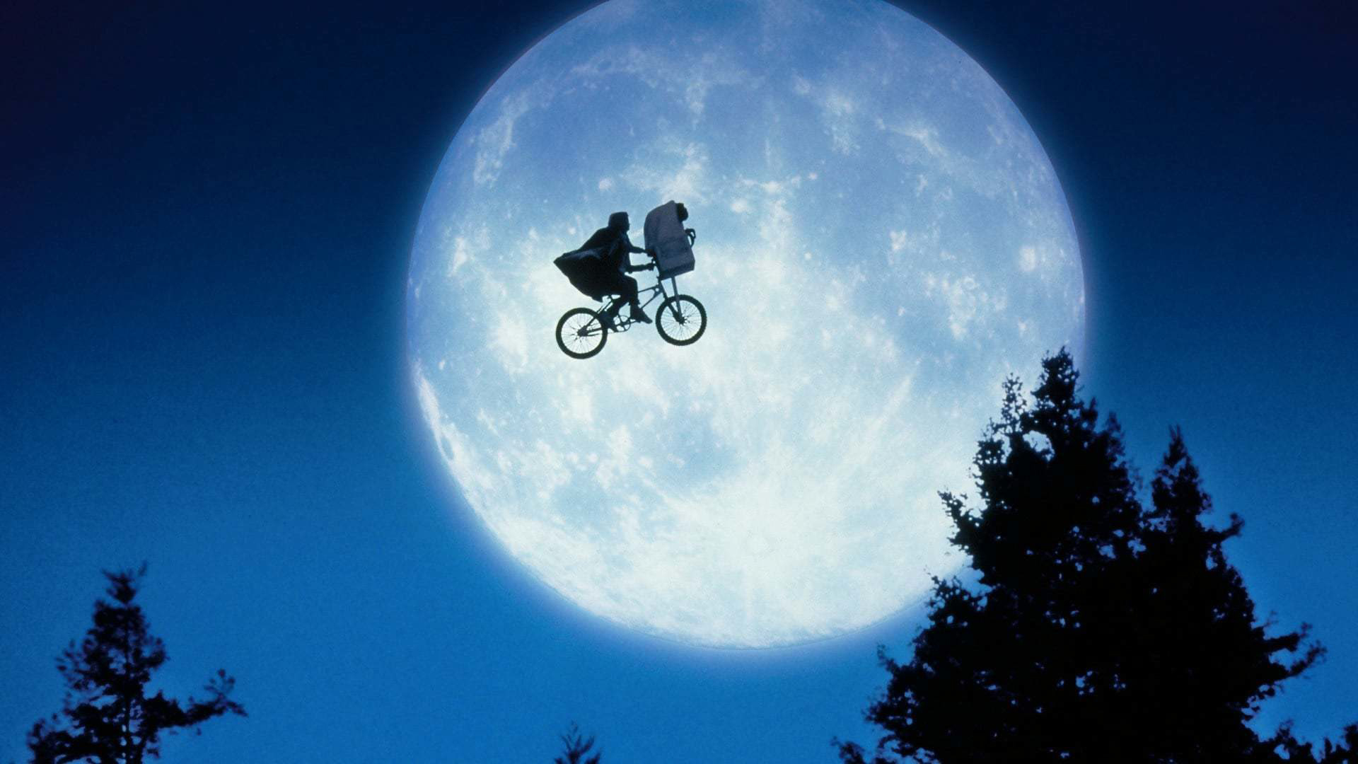 Een silhouet van een jongen die met een fiets door de lucht vliegt, tegen een achtergrond van een grote, volle maan.