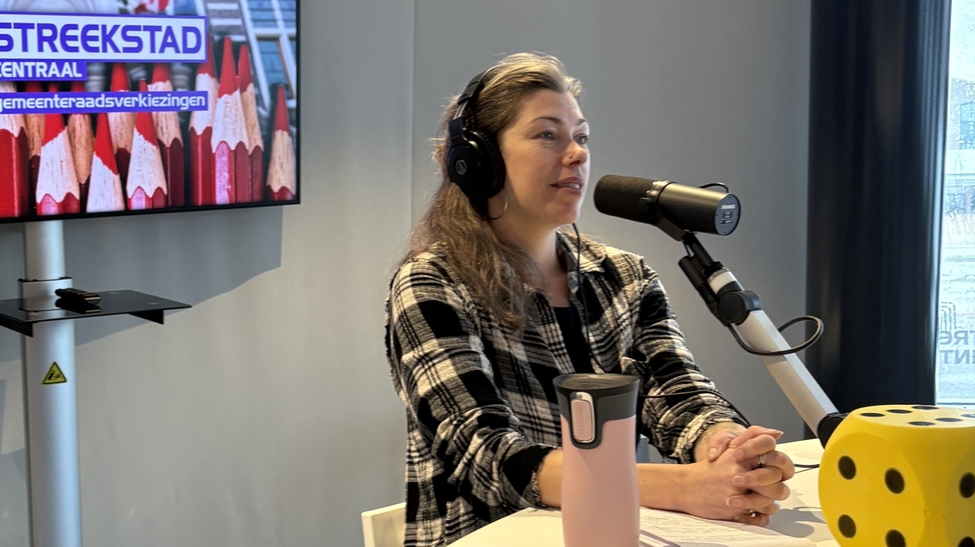 Vrouw met koptelefoon spreekt in microfoon in een studio. Op de achtergrond een scherm met "Streekstad Centraal" tekst.