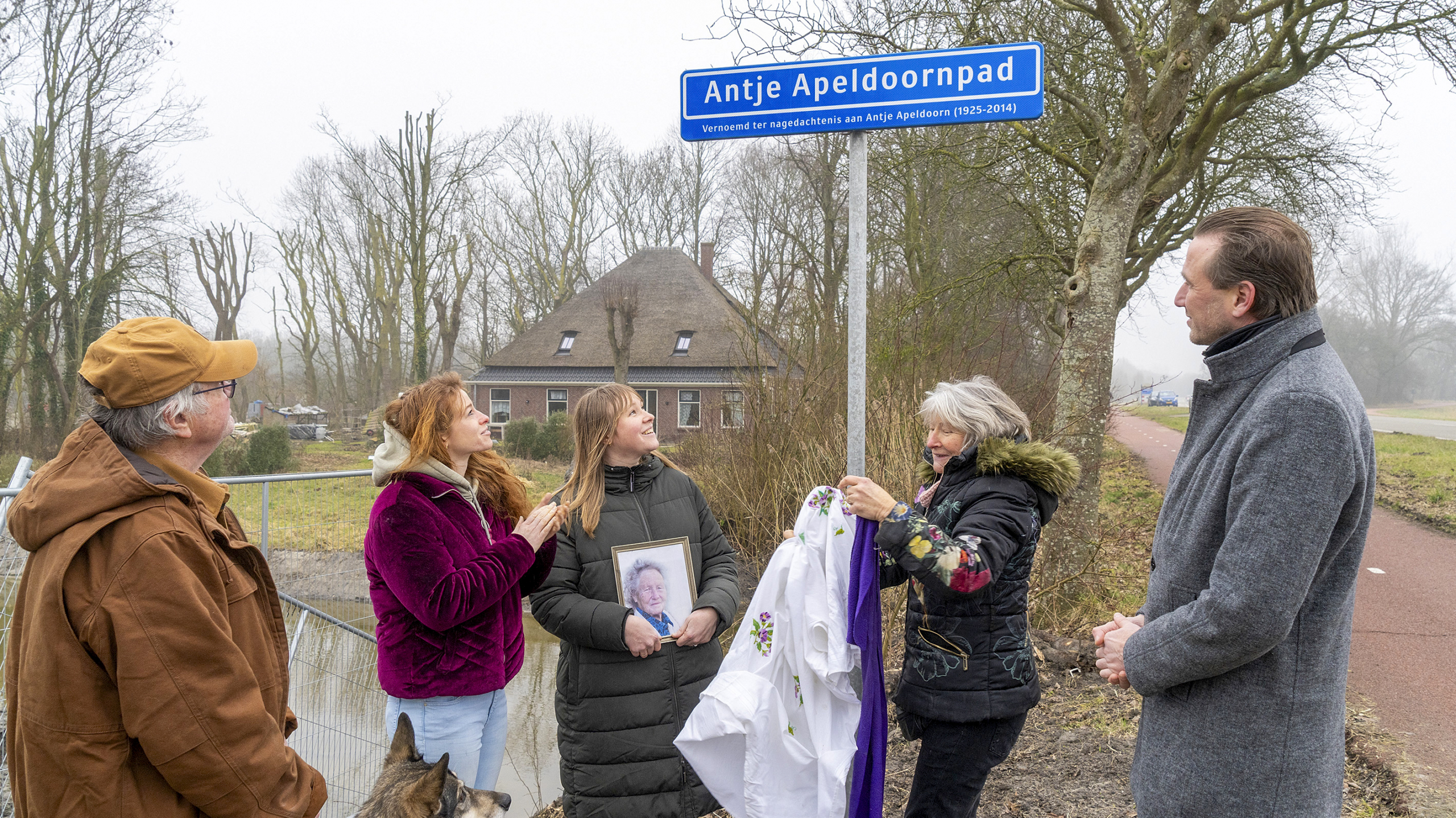 Groep mensen onthult een straatnaam "Antje Apeldoornpad" ter nagedachtenis aan Antje Apeldoorn.