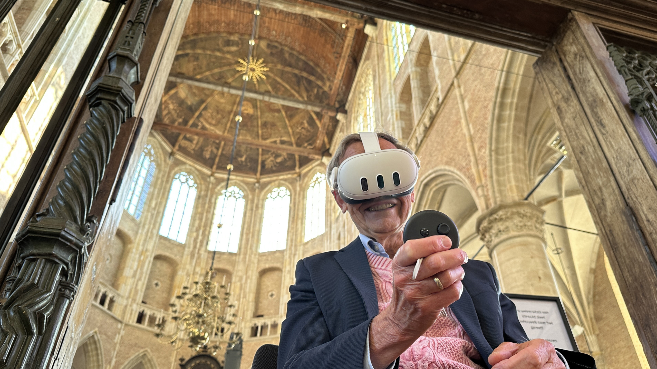 Man met VR-bril en controller in een historische kerk met hoge gewelven en kroonluchter.