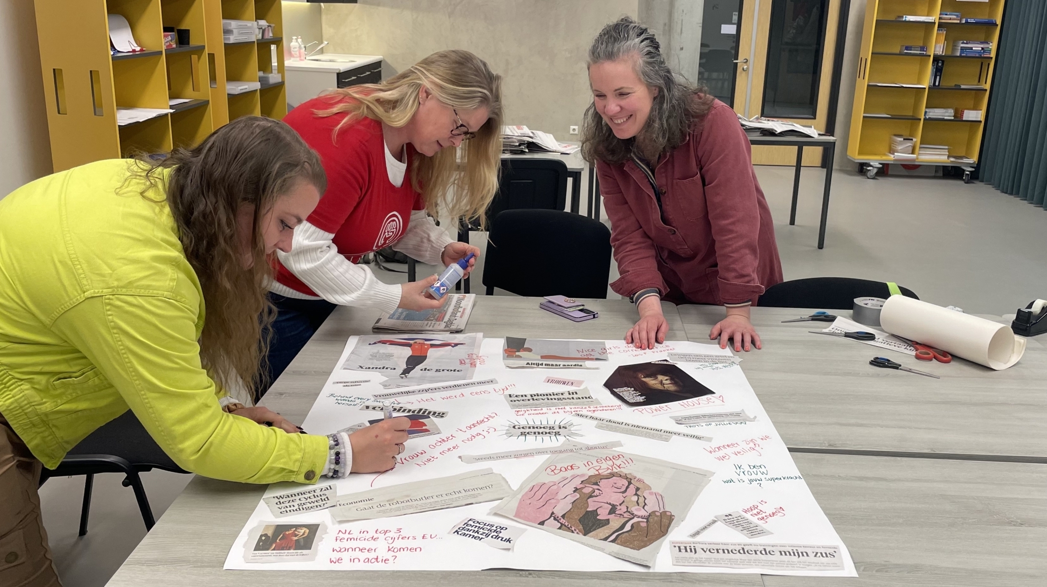 Drie vrouwen werken samen aan een tafel, bezig met creatieve collages en knutselmateriaal.