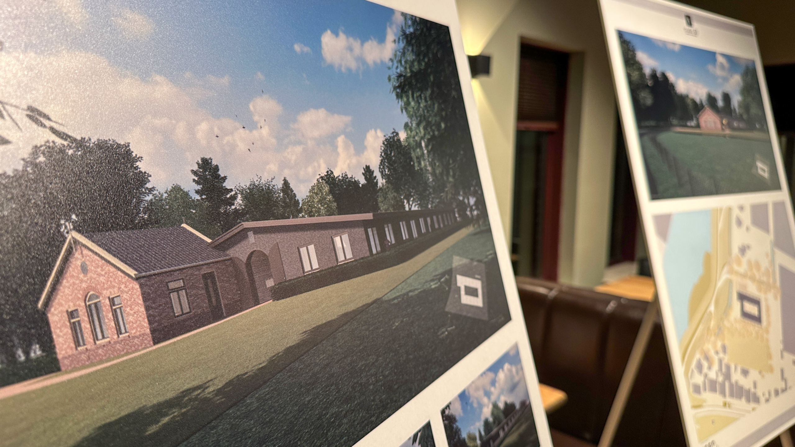 Borden met architecturale ontwerpen en plattegronden voor gebouwen, tentoongesteld in een binnenruimte.