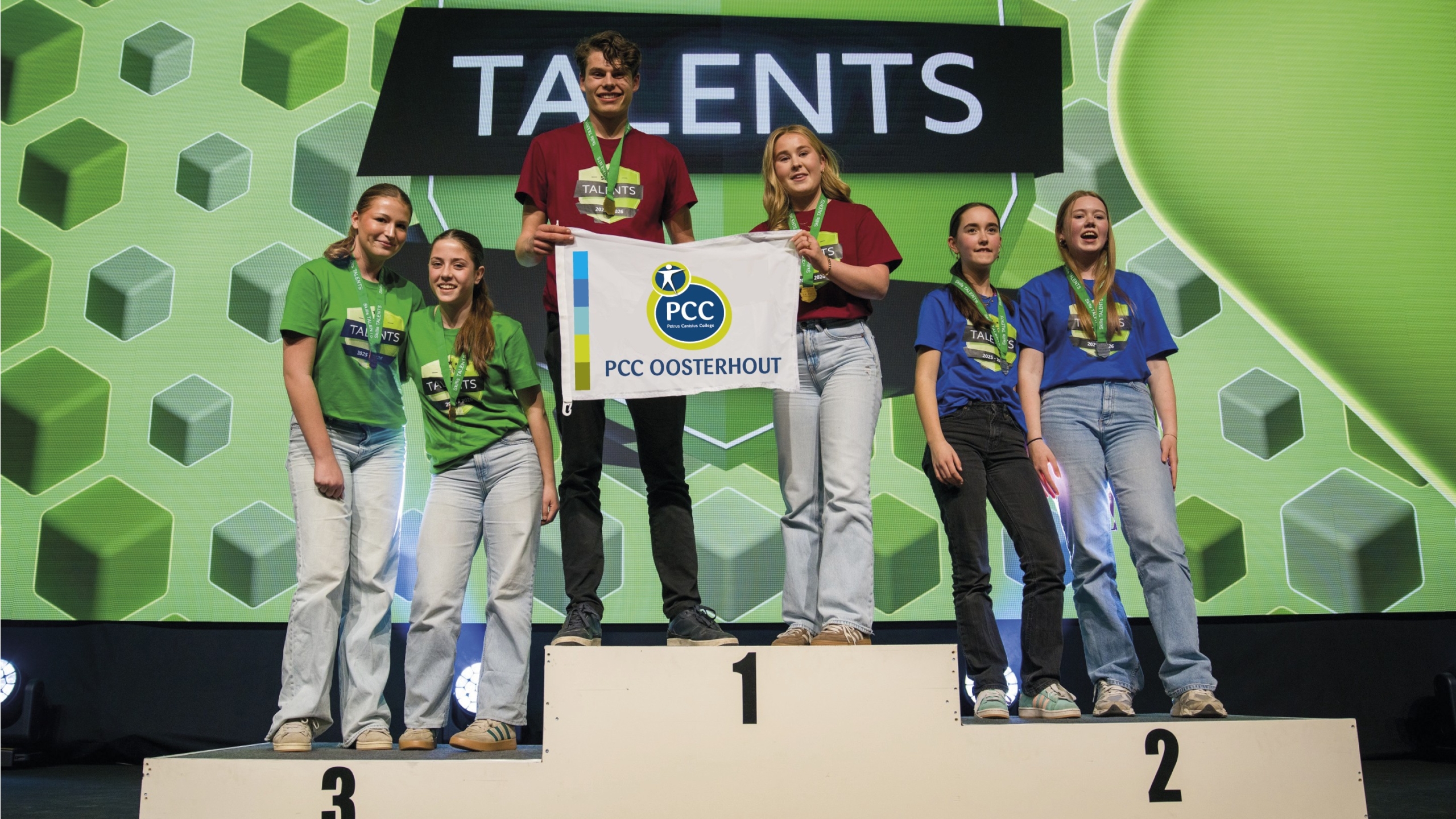 Zes jongvolwassenen staan op een podium met een banner van PCC Oosterhout; ze dragen medailles en gekleurde shirts.