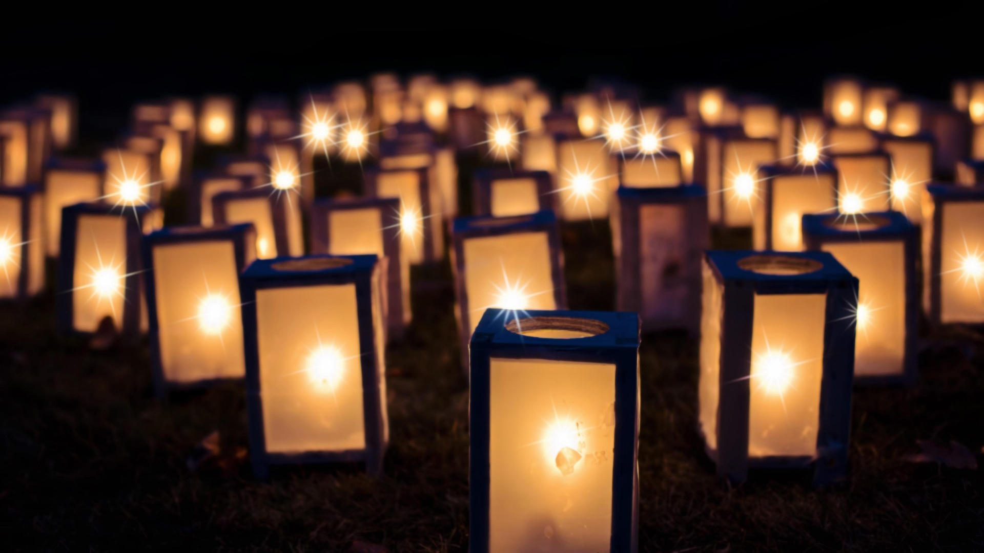 Vele sfeervol brandende lantaarns verlichten een donkere buitenomgeving.