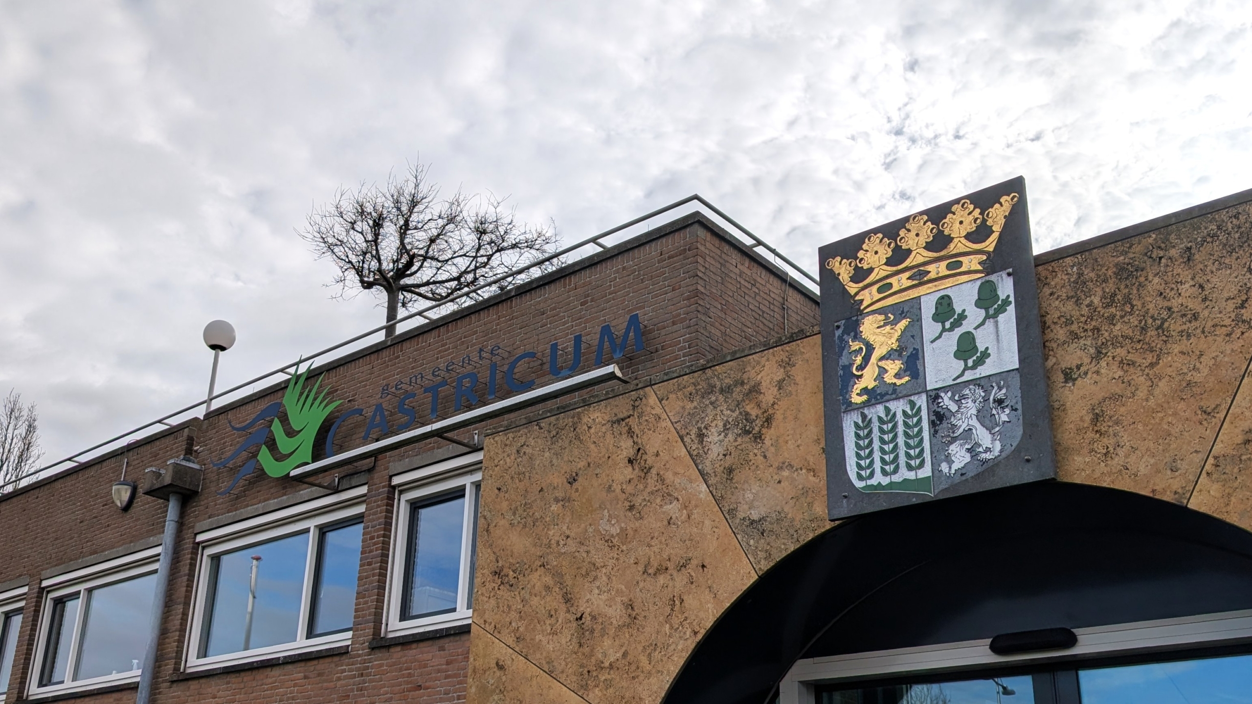 Gebouw met het logo van de gemeente Castricum en een wapenschild naast een ingang.