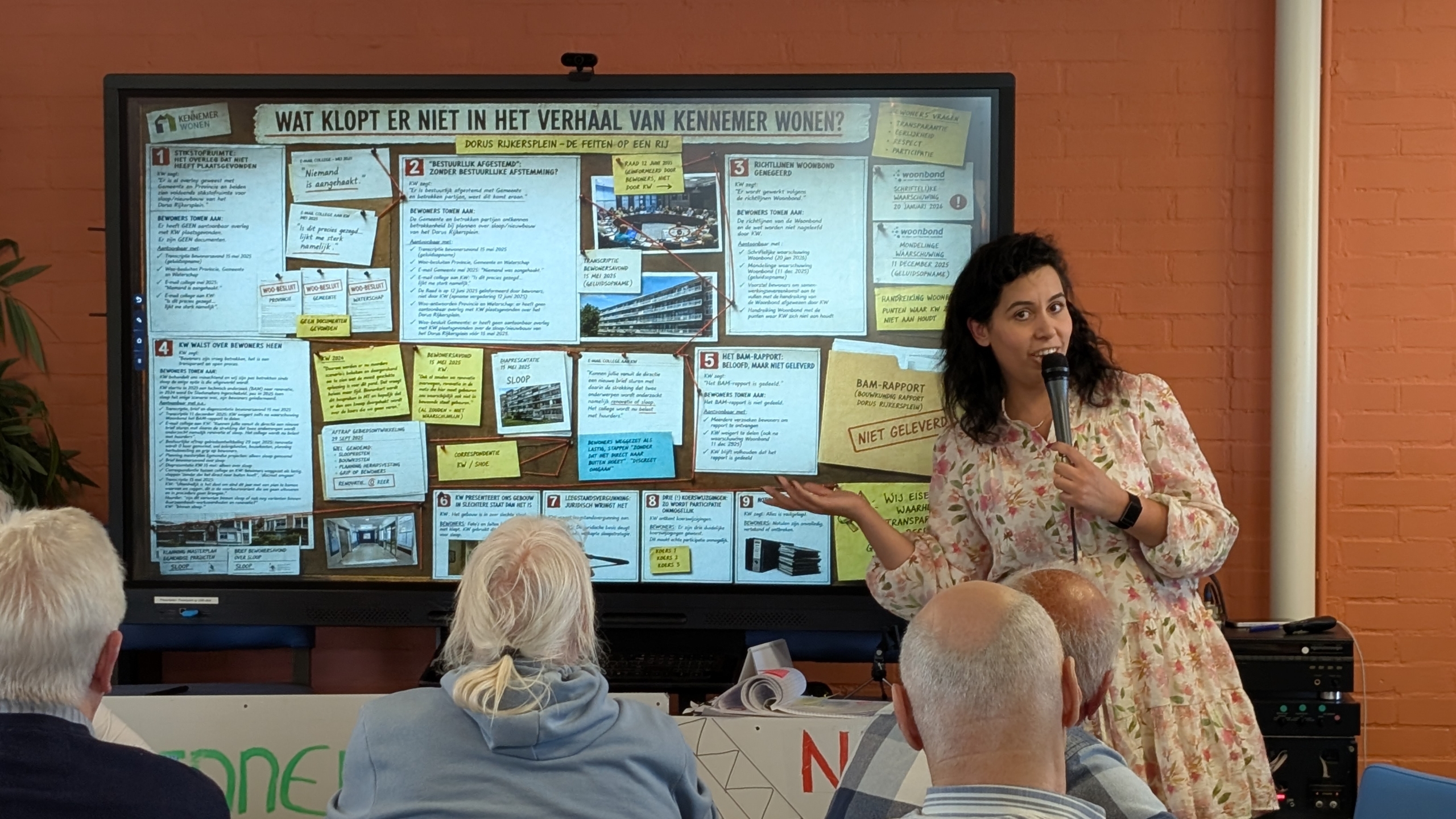 Vrouw geeft presentatie voor een scherm met tekst en afbeeldingen over het verhaal van Kennemer Wonen; publiek luistert aandachtig.
