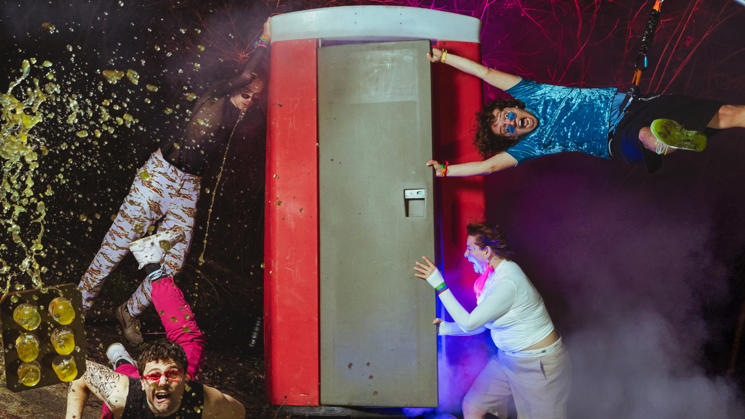 Mensen in kleurrijke outfits rond een omgevallen rood mobiel toilet, met vloeistofspetters en rook in de lucht.
