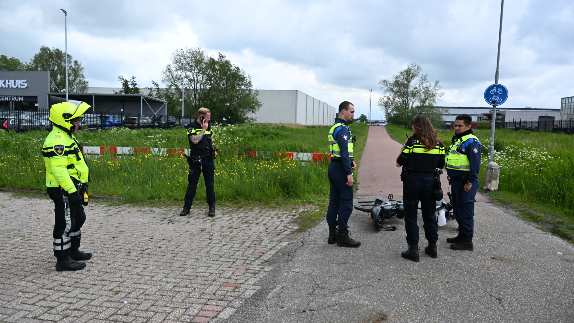 Politieagenten bespreken een incident met een omgevallen scooter op een fietspad.