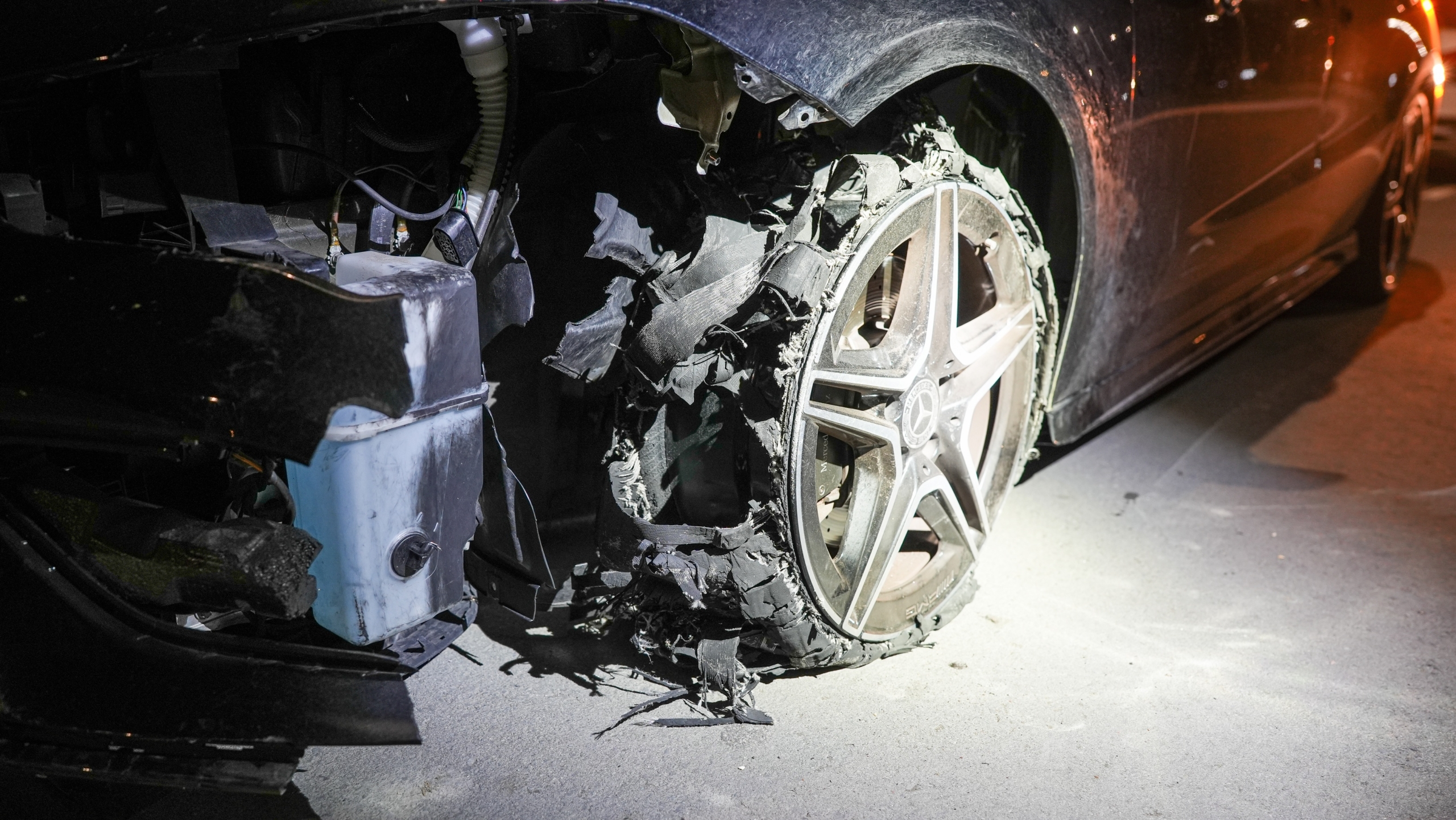 Auto met zwaar beschadigd wiel aan de rechter voorzijde, blootgelegd binnenwerk en afgescheurde bandenresten zichtbaar.