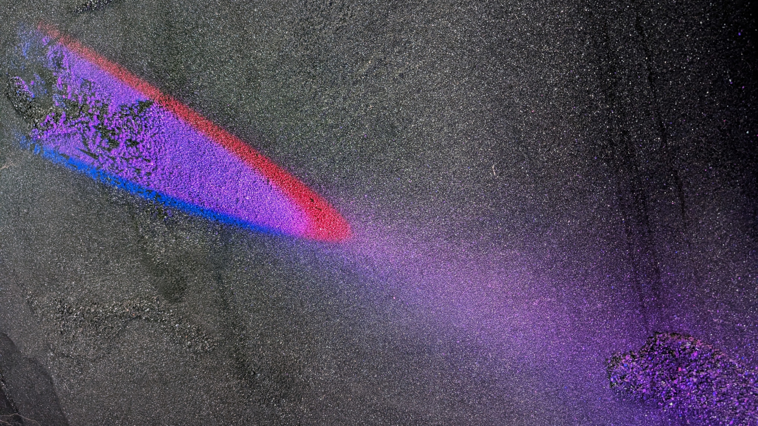 Rode en paarse lichtprojectie op een donkere, korrelige ondergrond.
