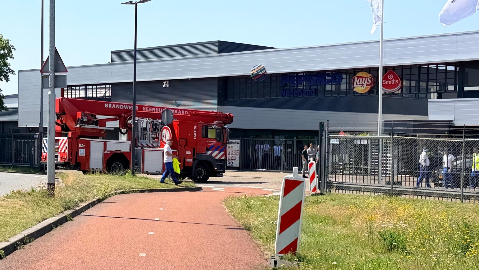 Een brandweerwagen staat geparkeerd buiten bij een gebouw met het logo van PepsiCo Nederland.