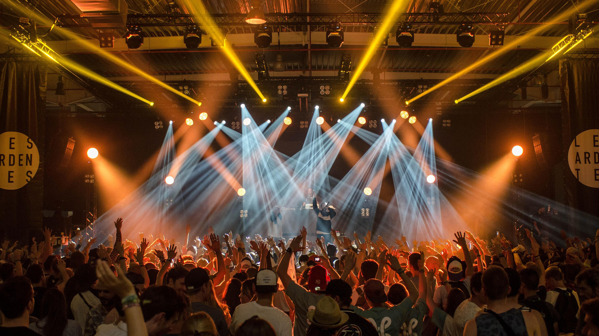 Publiek juicht tijdens een concert met felle lichten op het podium en een artiest die optreedt.