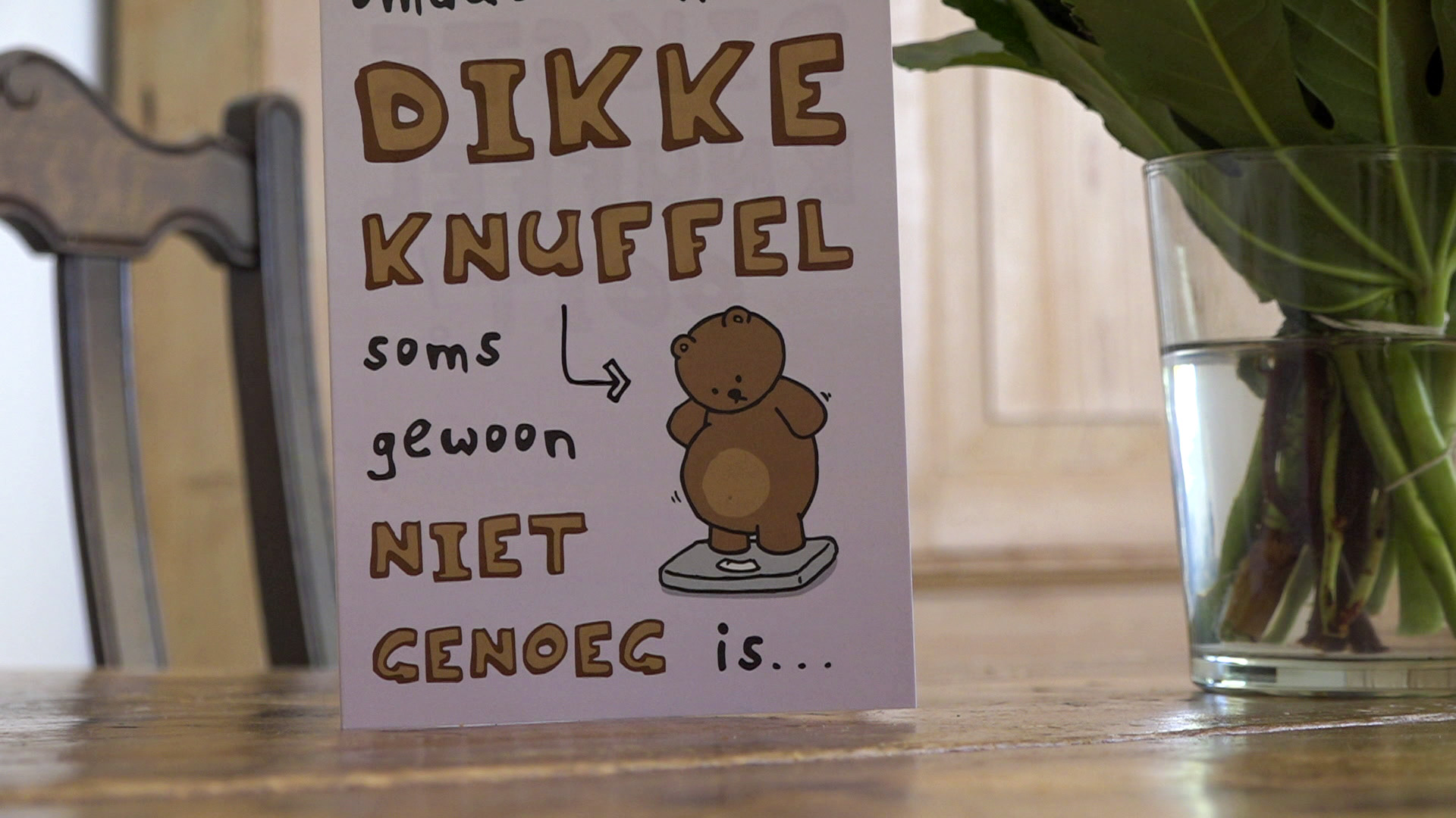 Kaartje op tafel met tekst: "Dikke knuffel soms gewoon niet genoeg is..." en een tekening van een beer op een weegschaal.