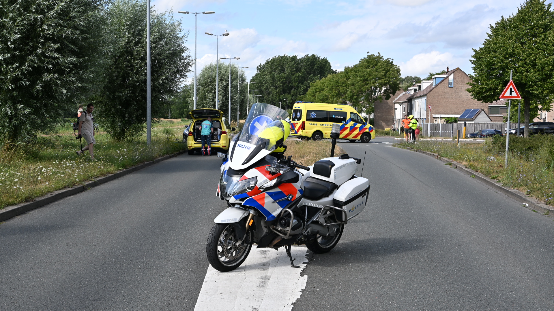 Politiemotor blokkeert de weg terwijl ambulance en hulpverleners verderop bij een incident in een woonwijk staan