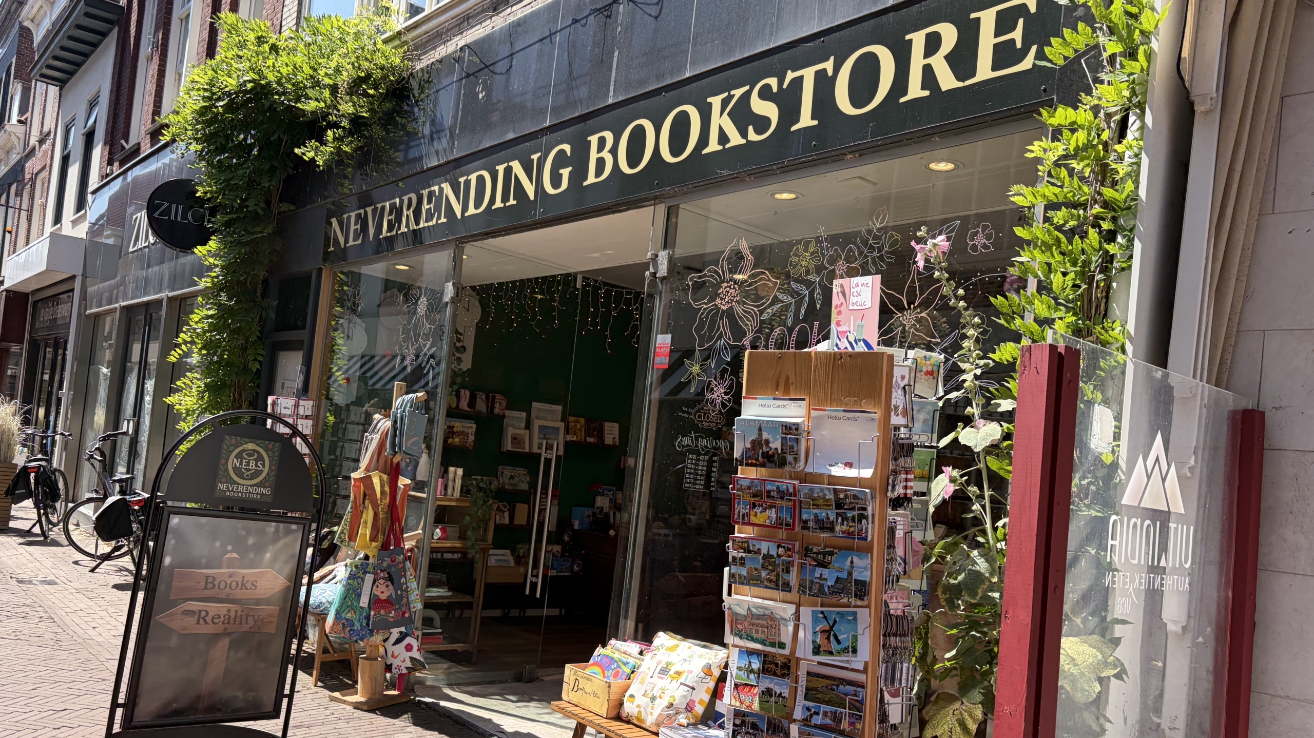 Gevel van Neverending Bookstore met etalage en rek met ansichtkaarten op een zonnige straat