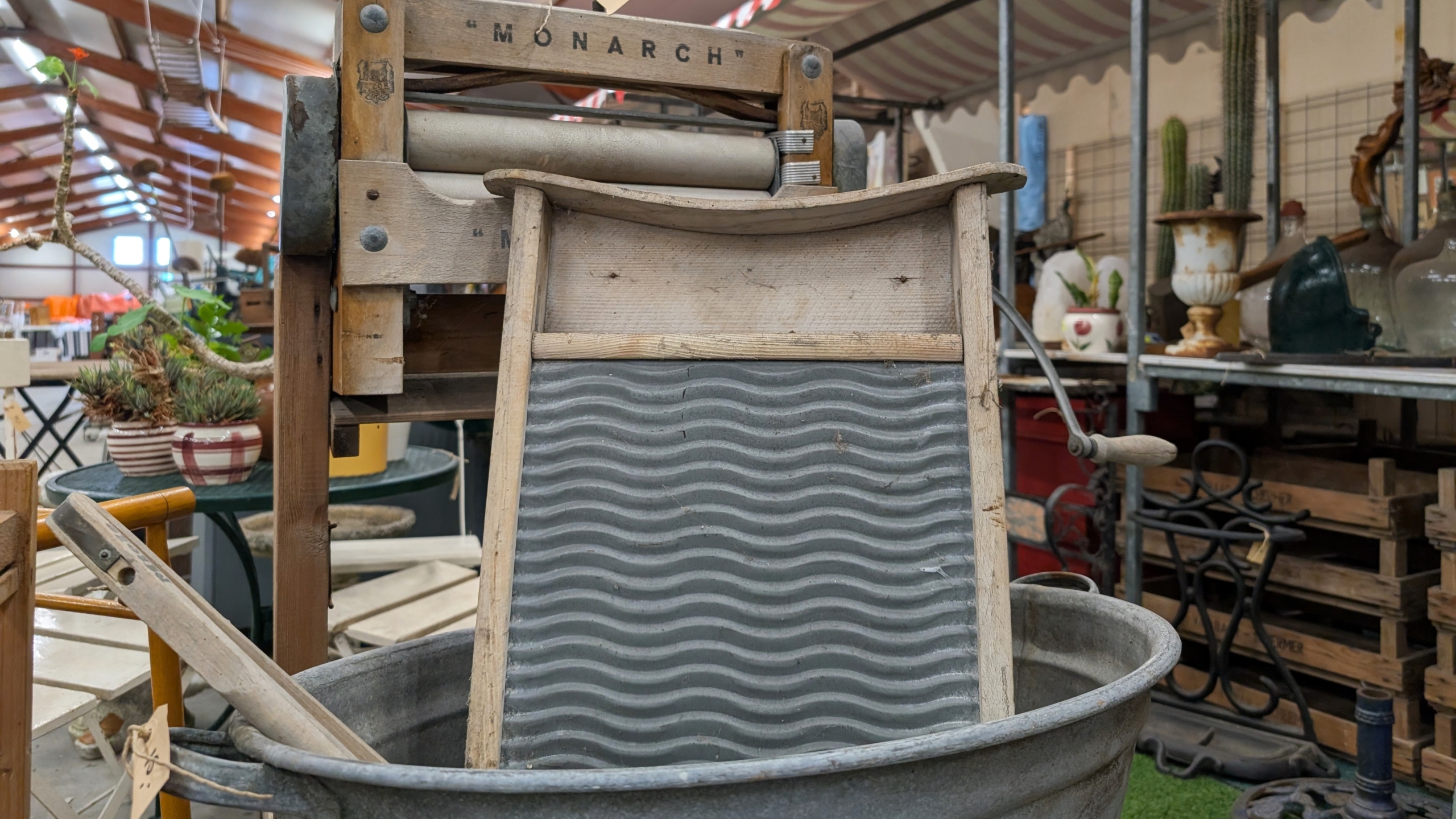 Ouderwets wasbord met geribbelde metalen plaat in een zinken teil, met houten wringer erboven op een rommelige markt