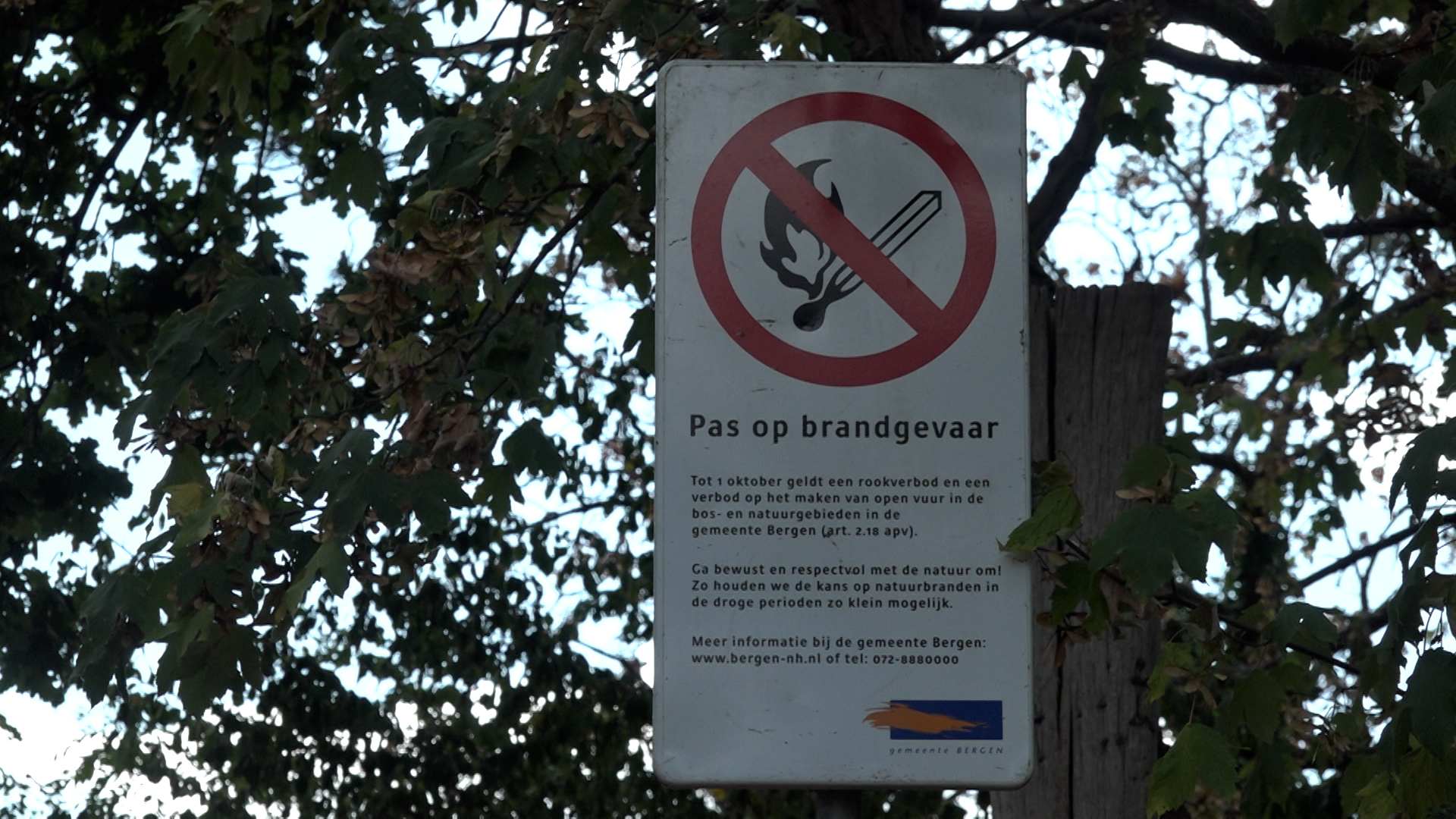 Waarschuwingsbord met verboden lucifer en tekst “Pas op brandgevaar” tussen bomen bij een natuurgebied