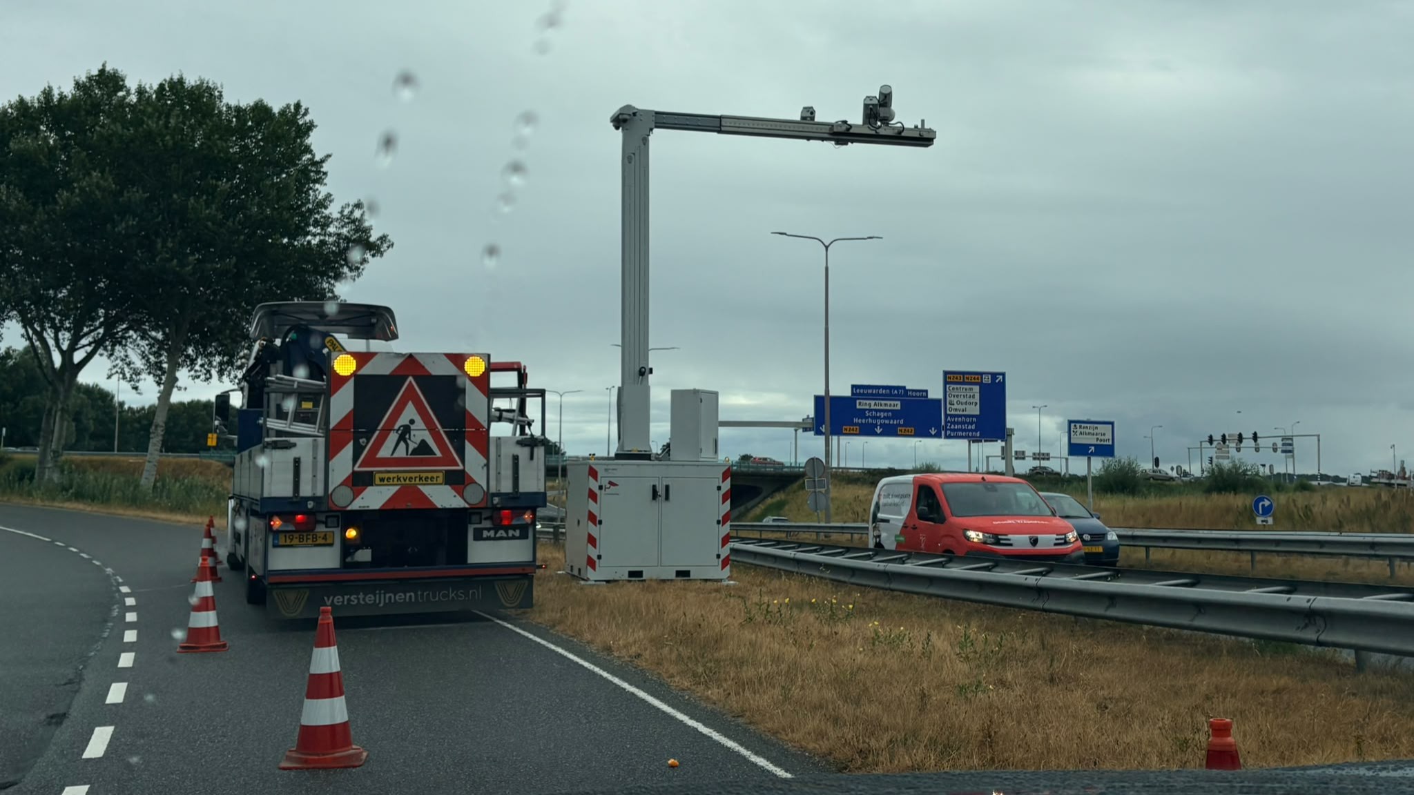Wegwerkzaamheden langs de snelweg met afgezette rijstrook, werkvoertuig met hoog platform en verkeer ernaast