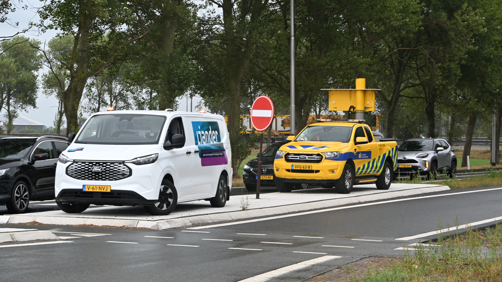 Witte Liander-bus en gele weginspectiepick-up met matrixbord geparkeerd langs een weg bij een verboden in te rijden bord