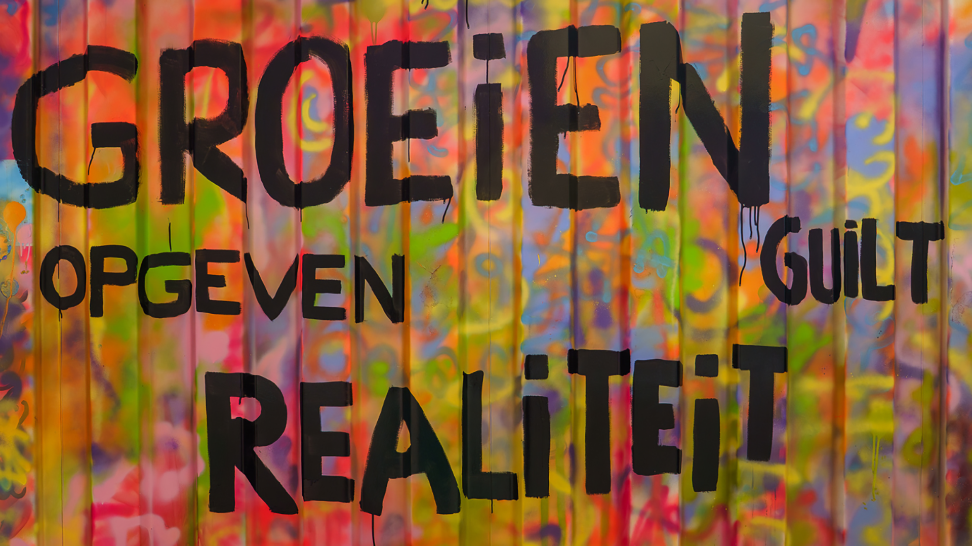 Graffiti op kleurrijke muur met de tekst Groeien opgeven guilt realiteit in zwarte letters