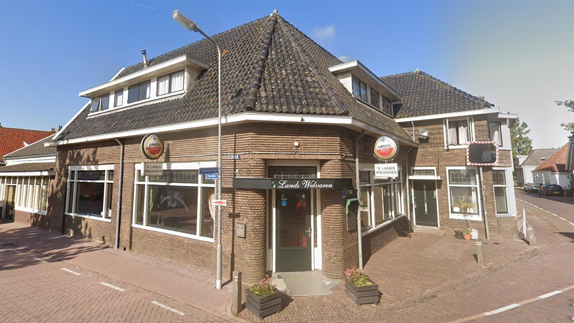 Hoekpand met café ’s Lands Welvaren, bruin baksteen en groot pannendak, met Amstel-bierborden aan de gevel
