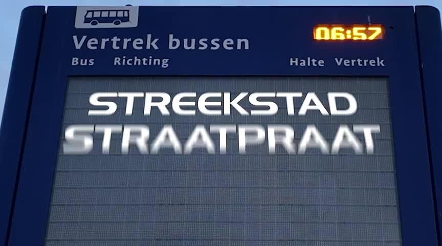 Digitaal bord met Vertrek bussen en tijd 06:57, met grote tekst STREEKSTAD STRAATPRAAT