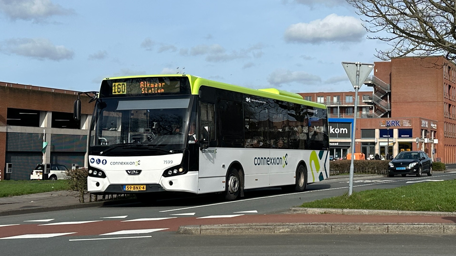 Witte Connexxion-bus op de weg met lijnnummer 160 en bestemming Alkmaar Station, met gebouwen op de achtergrond