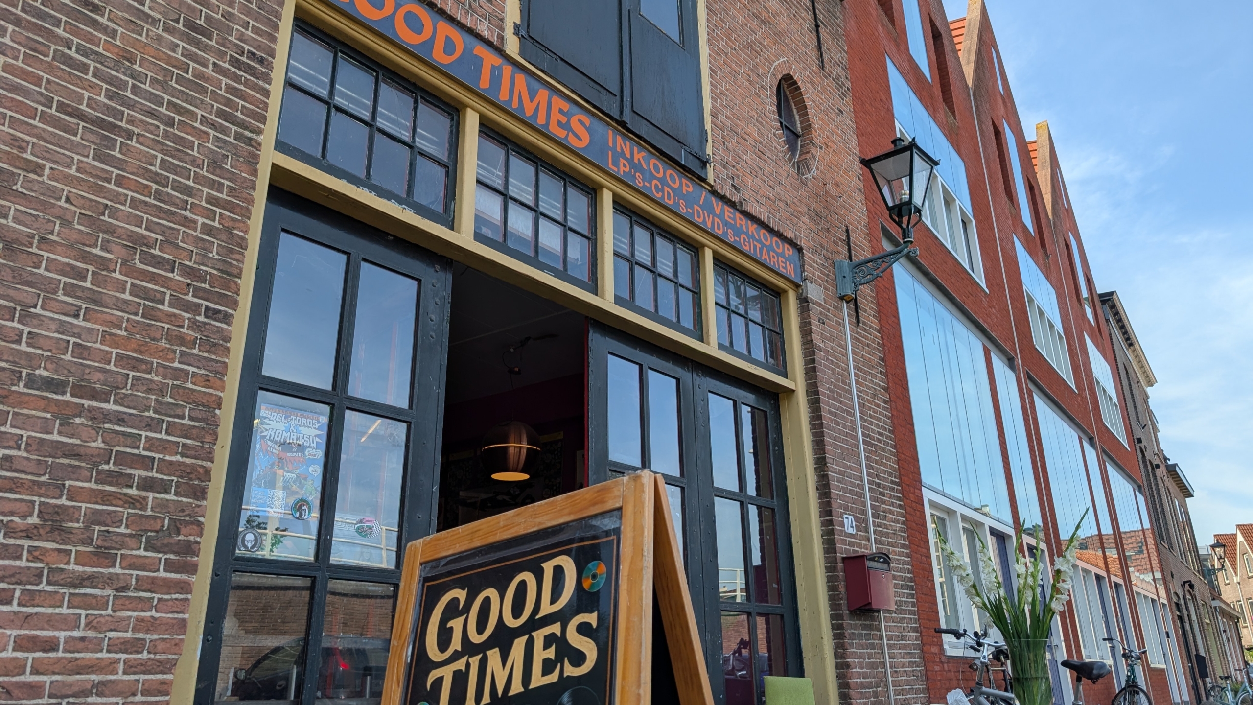Gevel van winkel Good Times met open deur, uithangbord “Good Times” en tekst over inkoop/verkoop lp’s, cd’s, dvd’s en gitaren