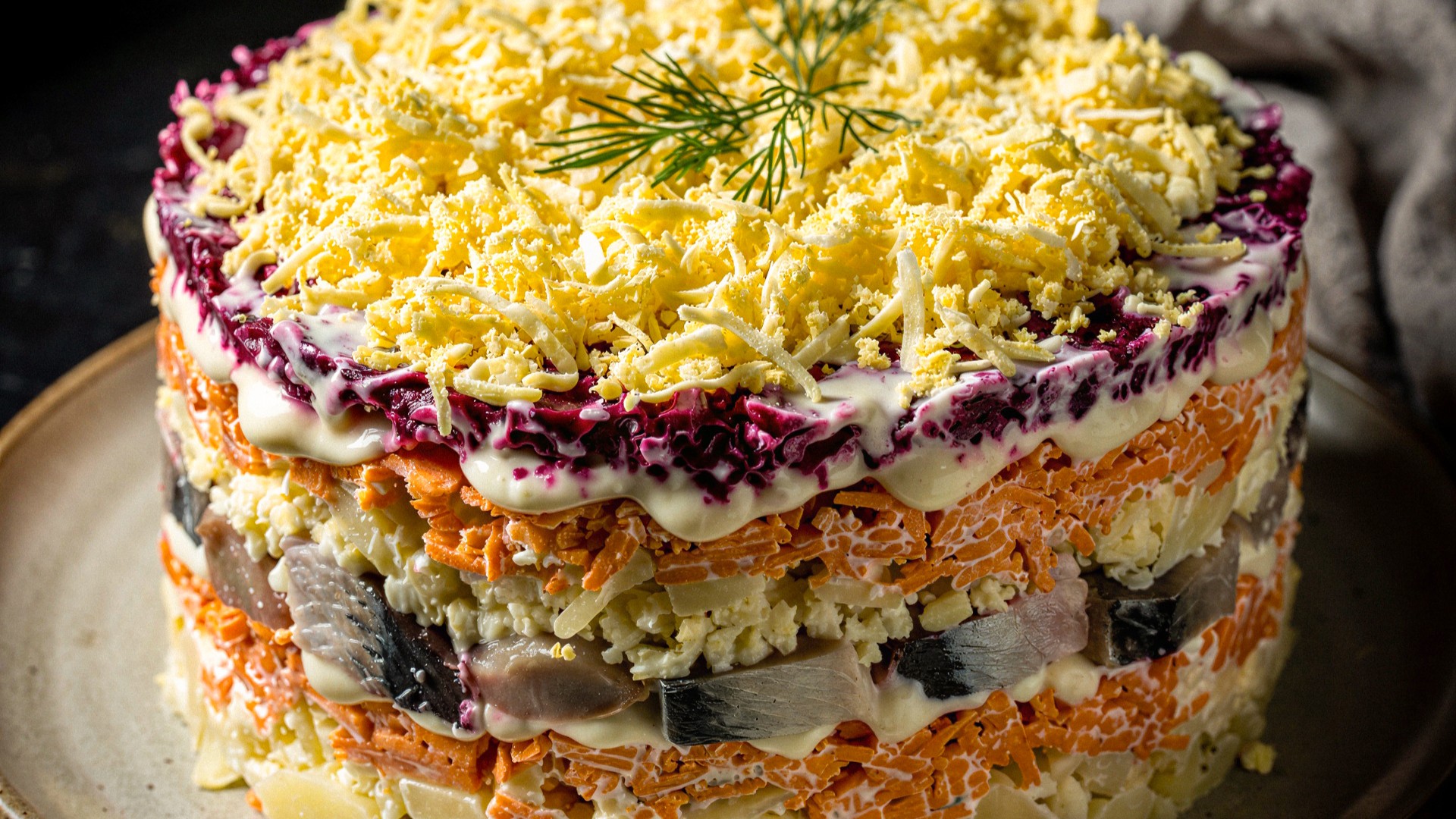 Gelaagde salade zoals haring onder een bontjas met lagen groenten, mayonaise en geraspte eieren, gegarneerd met dille