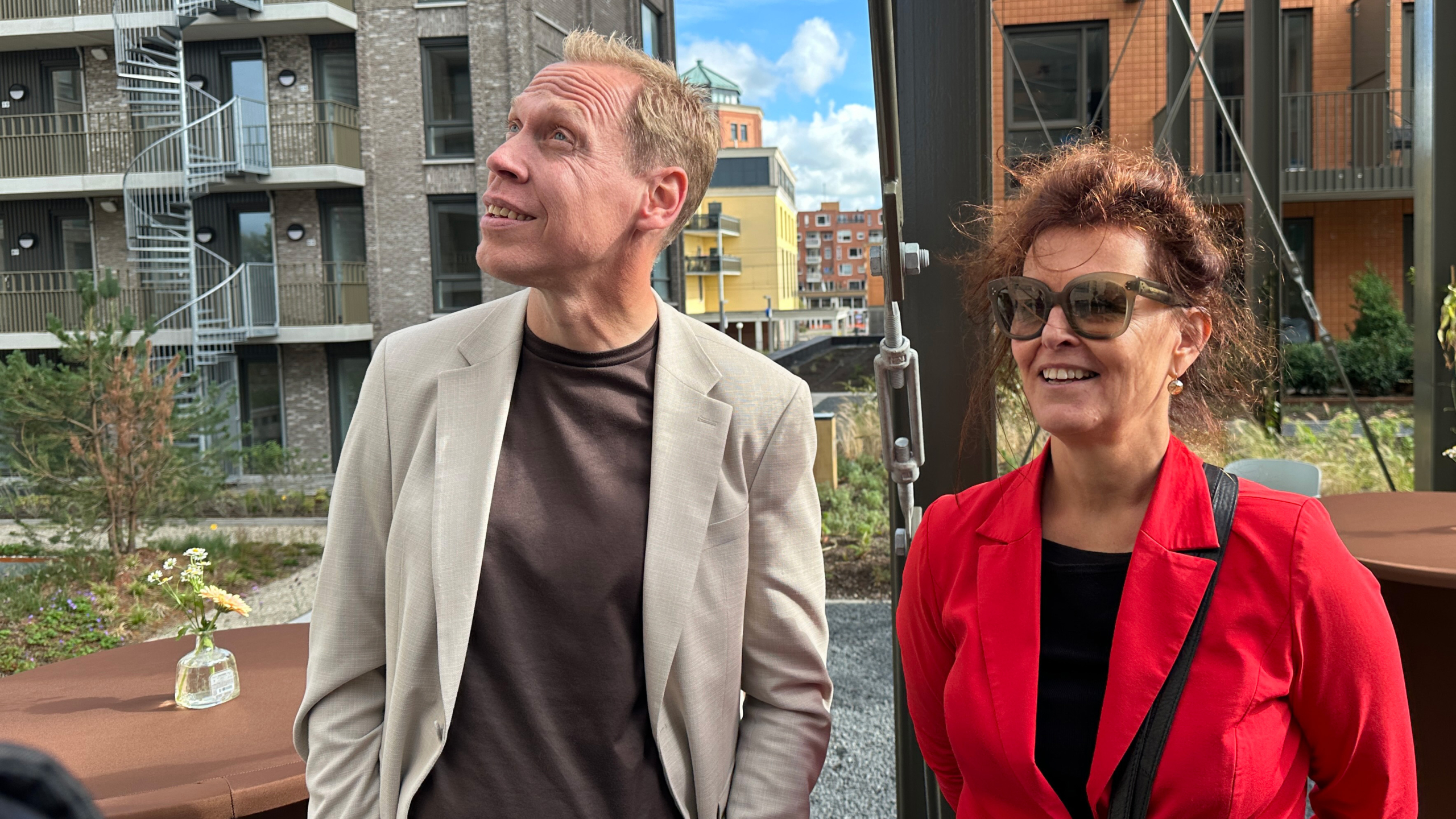 Man en vrouw kijken omhoog in een moderne binnentuin met appartementengebouwen op de achtergrond