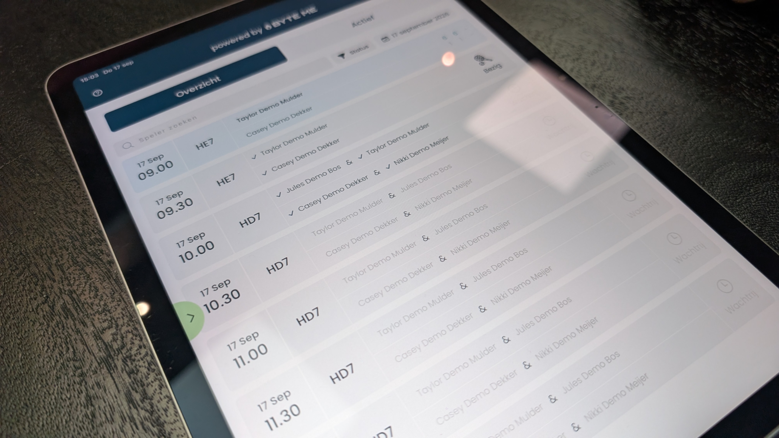 Tablet met planningsoverzicht op het scherm, met tijden en spelersnamen, gefotografeerd schuin van boven