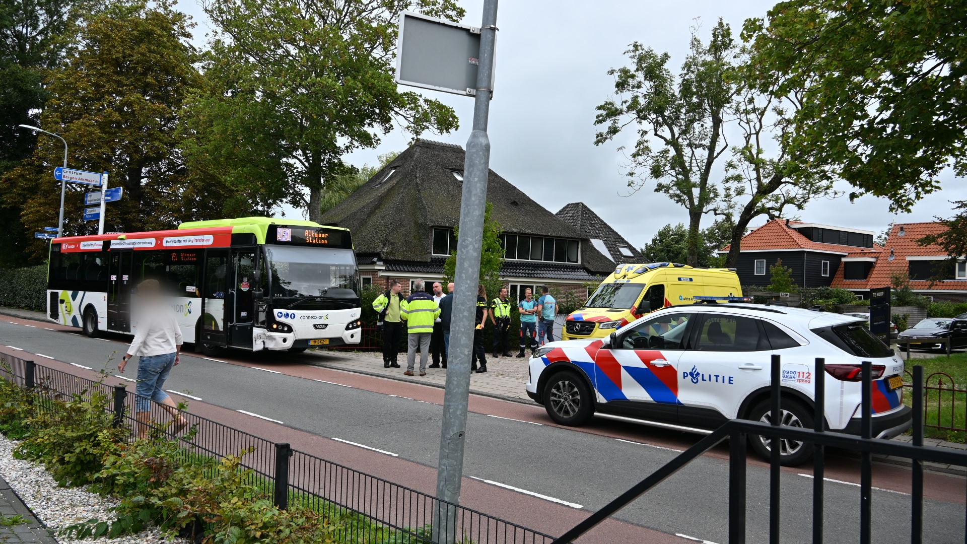 Lijnbus met bestemming Alkmaar Station staat stil bij politieauto en ambulance terwijl hulpdiensten overleggen langs de weg