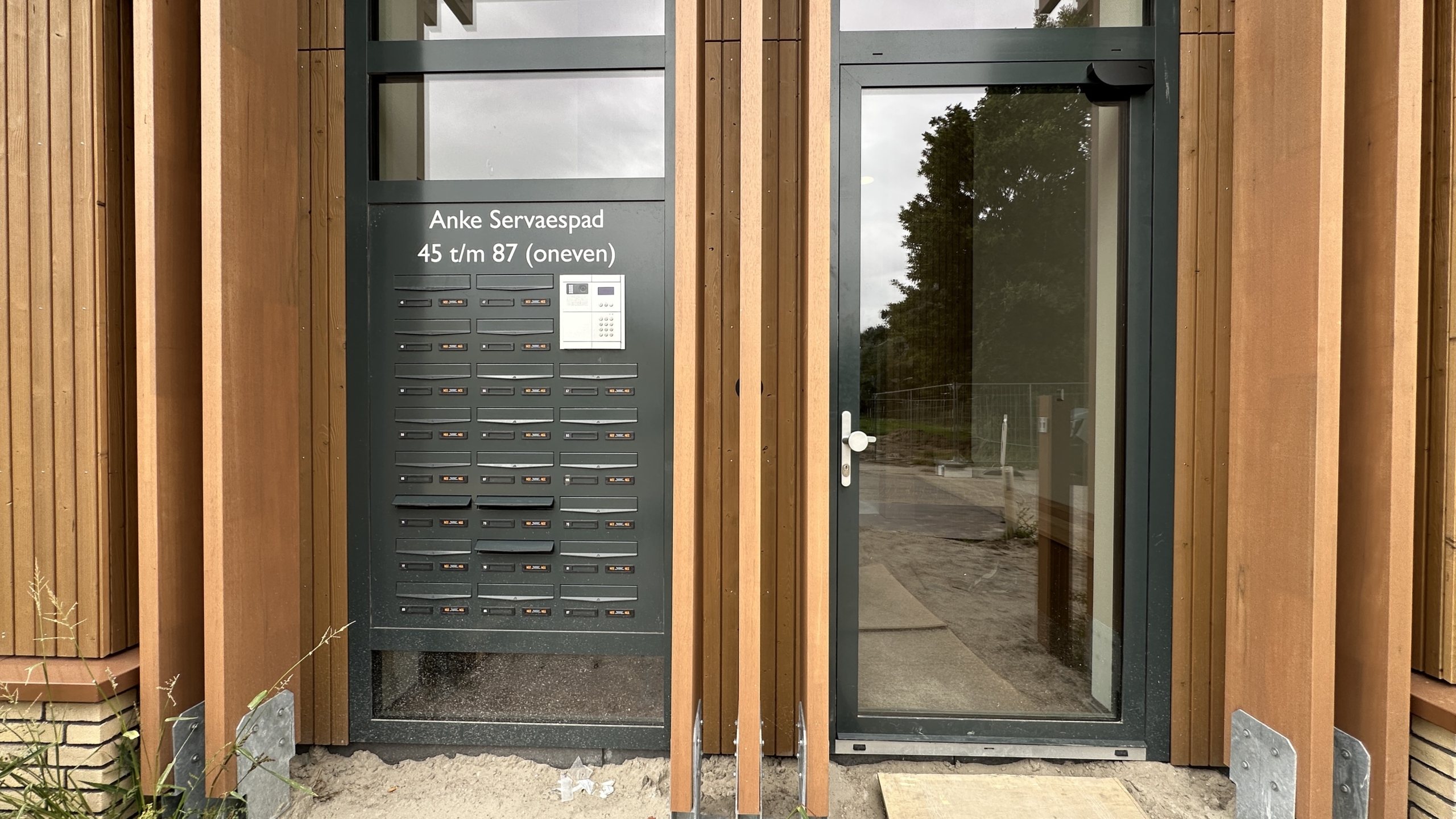 Entree met brievenbussen en intercom, met tekst “Anke Servaespad 45 t/m 87 (oneven)” naast glazen deur