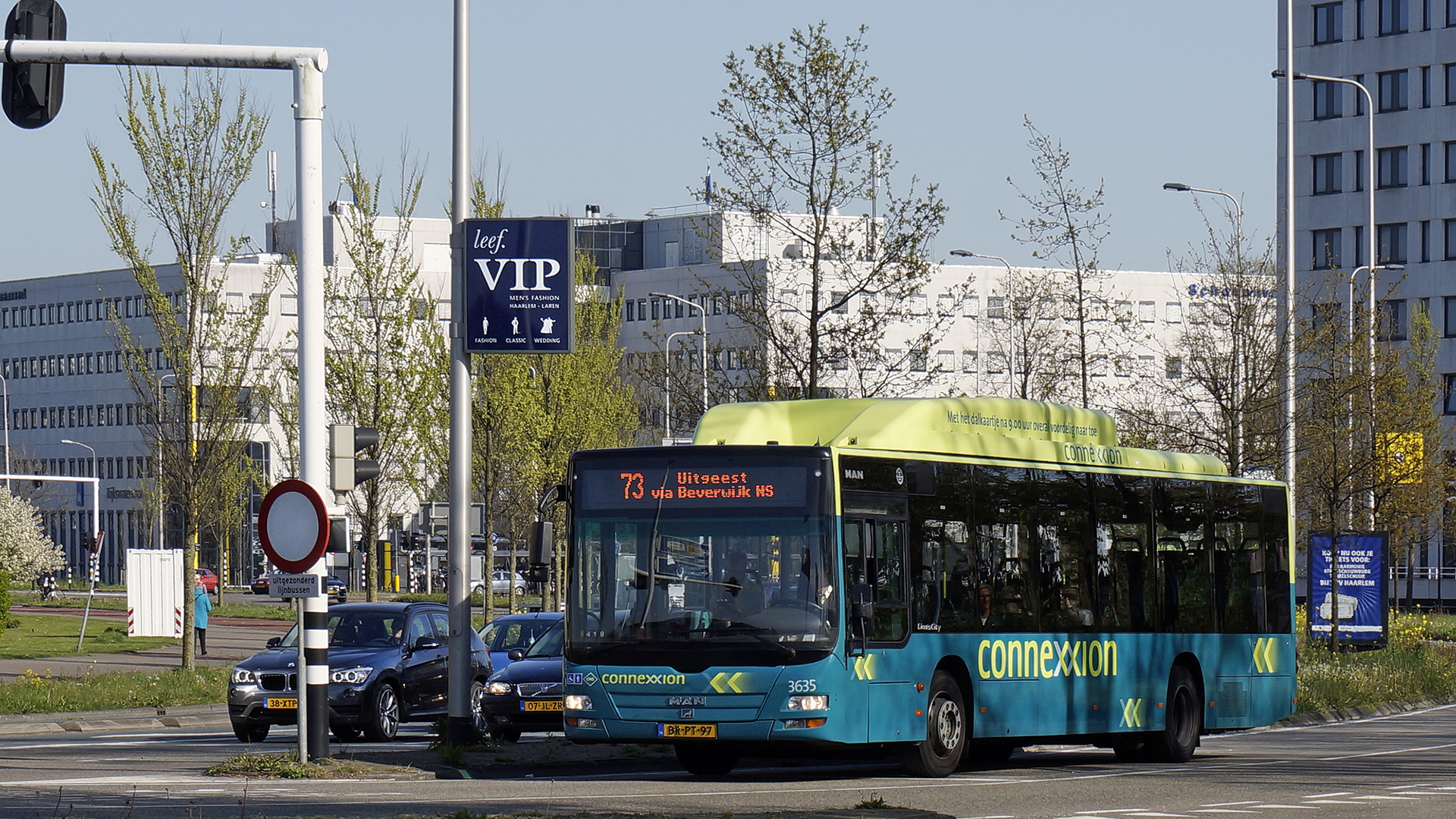 Connexxion-stadsbus lijn 73 richting Uitgeest via Beverwijk NS rijdt door een kruispunt met auto’s en kantoren op de achtergrond