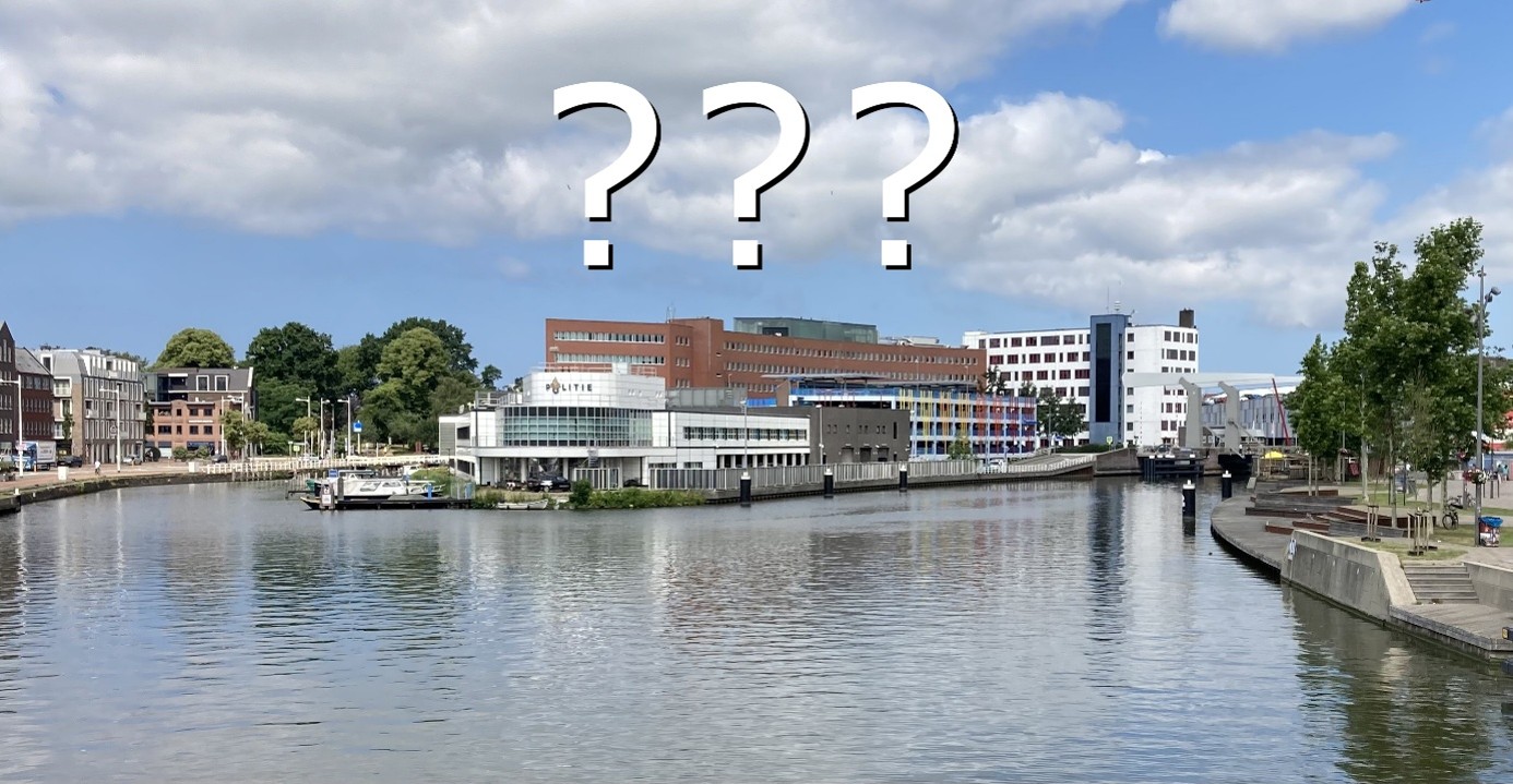Uitzicht over een kanaal met gebouwen langs de kade; bovenin staan grote vraagtekens (???) in beeld